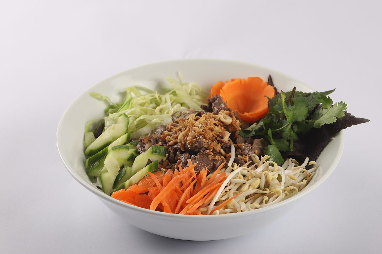 A bowl of bún bò Nam Bộ with herbs and pickled carrot